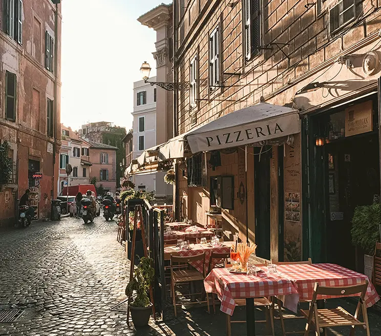 Stradina caratteristica di Roma con un ristorante e tavoli all'aperto, ideale per rilassarsi e gustare cibi locali.