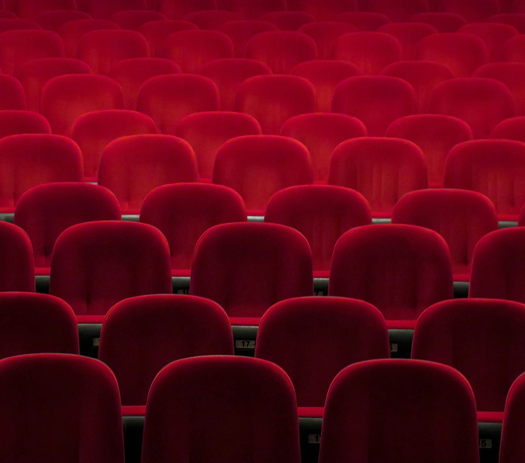File di poltrone rosse in una sala cinematografica vuota, simbolo dell'offerta cinema nella capitale