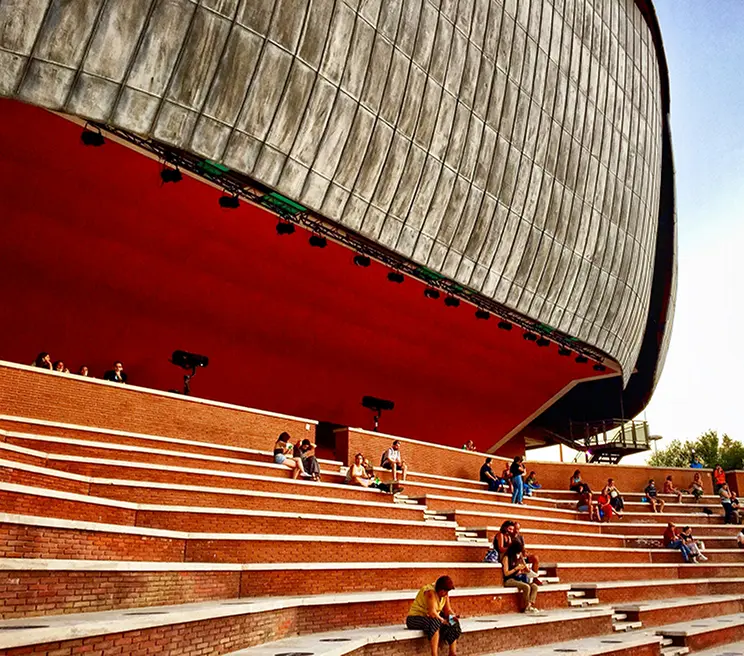 Vista dell'Auditorium Parco della Musica con persone sedute sugli scalini, luogo iconico per eventi e concerti a Roma